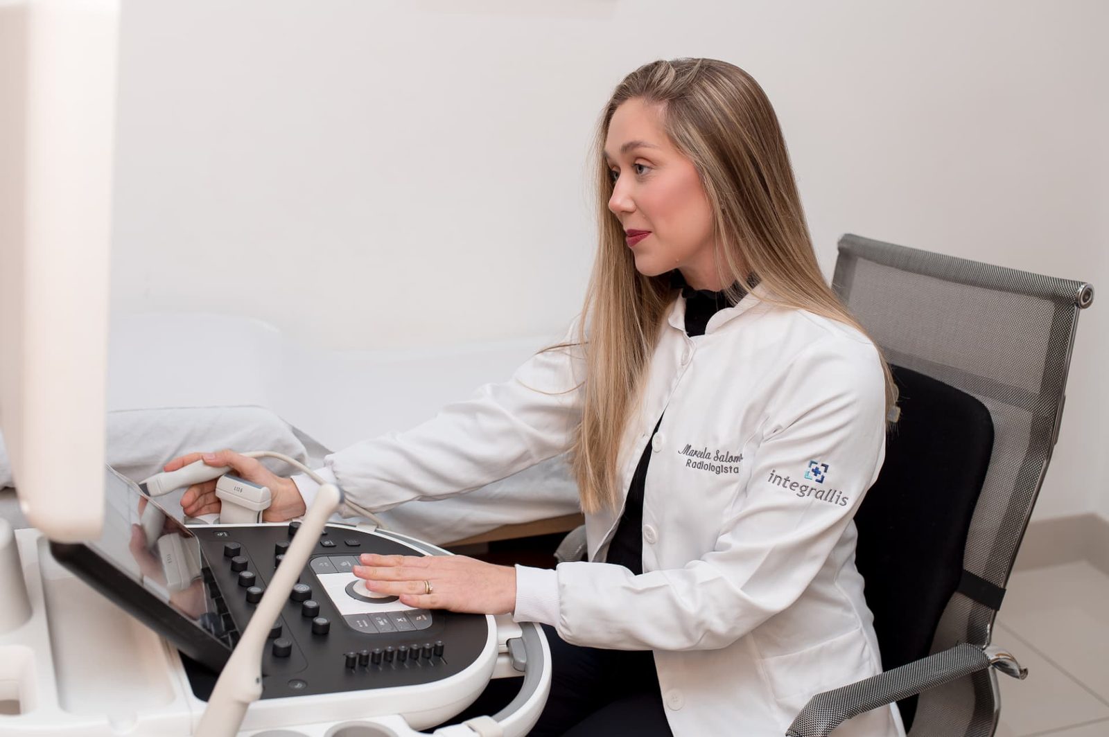 Dra. Marcela Salomon realizando um exame de ultrassonografia com Doppler, observando as imagens no aparelho